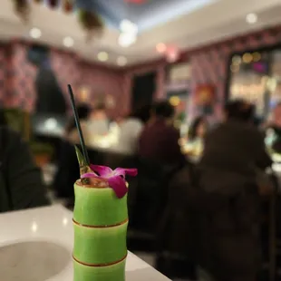 a green drink with a pink flower in it