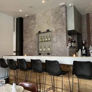 a bar with black chairs and a brick wall