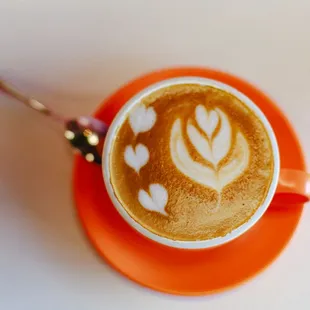 a cup of cappuccino on an orange saucer