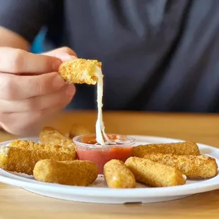 a person dipping a piece of tater tots