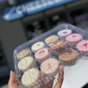 a hand holding a box of cupcakes