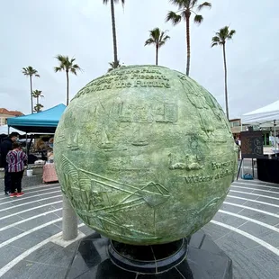 a large green globe in a plaza