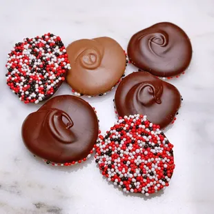 four chocolate covered cookies with sprinkles