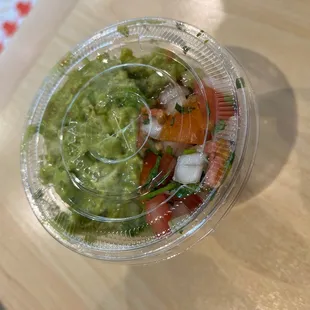 a plastic container filled with guacamole