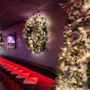 a row of bar stools in front of a christmas tree