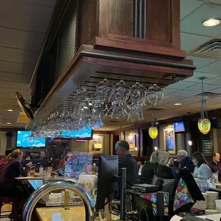 people sitting at a bar with wine glasses hanging from the ceiling