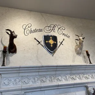 a fireplace with deer heads and a shield on the mantle