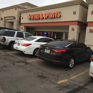 several cars parked in front of a wine and spirits store