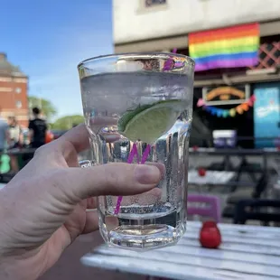 a person holding a glass of water with a lime slice in it