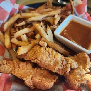 Kids chicken tenders with side if fries and BBQ sauce.