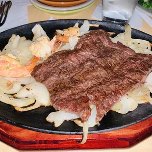 a steak on a plate with onions and shrimp