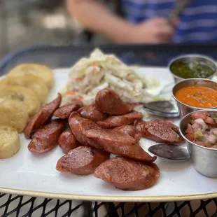 a plate of sausage, bread, and coleslaw
