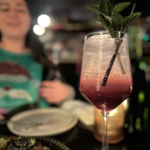 a woman sitting at a table with a drink