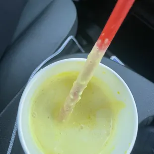  cup of yellow liquid with a straw sticking out of it