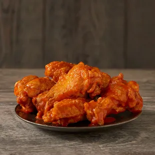 a plate of buffalo wings on a wooden table