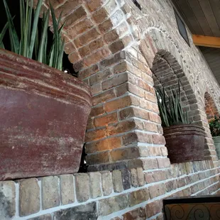 a brick wall with potted plants