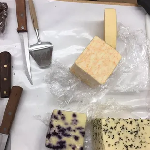 A sampling of cheese. Lower left: blueberry, lower right: horseradish havarti, top: two types of cheddar.