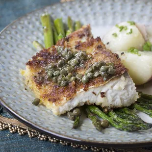a plate of fish with asparagus and potatoes