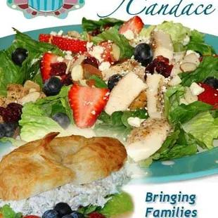 a plate of salad with chicken, strawberries, and blueberries