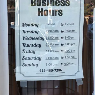 a business hours sign in a window