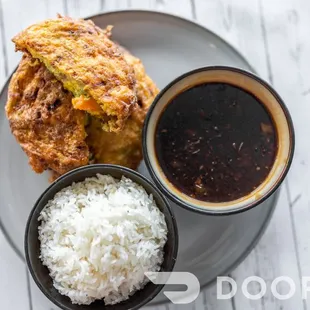 a plate of fried chicken with rice and dipping sauce