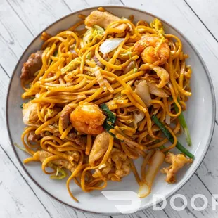 a plate of noodles with shrimp and vegetables