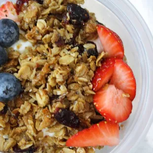 a bowl of granola with strawberries and blueberries