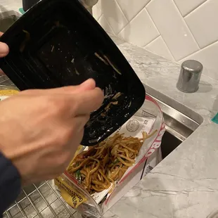 a person holding a tray of noodles