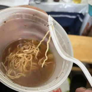 a person holding a bowl of noodles