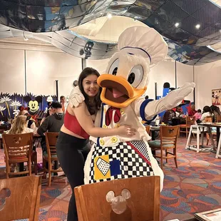 a woman hugging a duck mascot