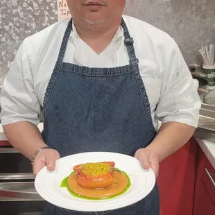 Holding a plate of stuffed red peppers with orzo pasta, romesco sauce, and herb oil