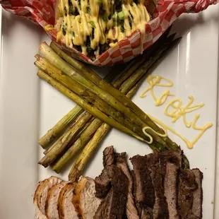 Ribeye steak with chicken served with loaded broccoli and shrimp cheese baked potato with asparagus.