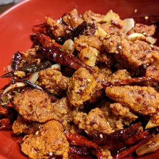 dry chili chicken  Crispy hunks of chicken wok tossed with ginger, garlic, scallion and lots of Thai chilies and Sichuan peppercorns.