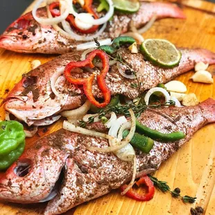 three whole fish on a cutting board