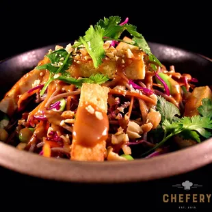 Asian flavors are packed in this protein bowl of noodles and vegetables, topped with seared tofu, crushed peanuts, and tangy peanut dressing