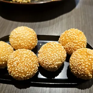 five sesame balls on a black plate