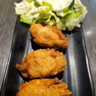 three pieces of fried chicken on a black plate