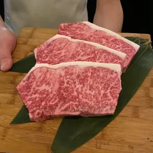 a person holding a chopping board with raw meat on it