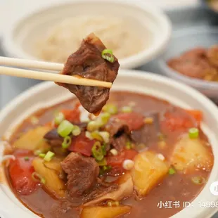 a bowl of stew with chopsticks