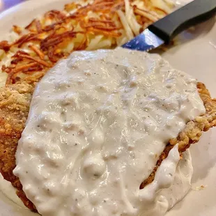 a plate of food with gravy and hash browns