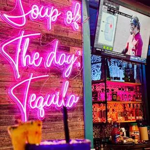 a neon sign that says soup of the day tequila