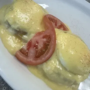 a plate of eggs benedict with tomatoes