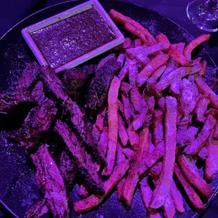 a plate of steak and fries with dipping sauce