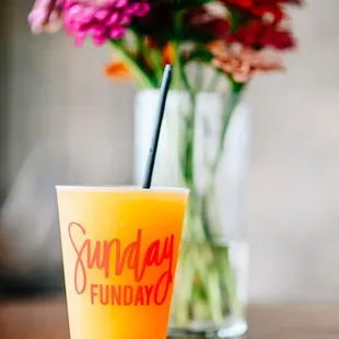 a glass of orange juice and a vase of flowers