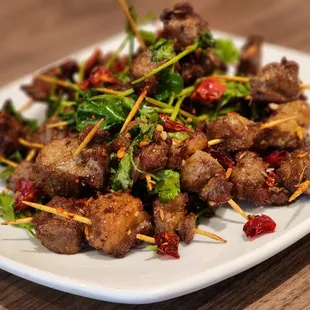 a plate of meat skewered on toothpicks