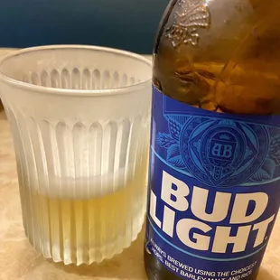 a bottle of bud light next to a plastic cup