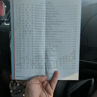 a hand holding a menu in a car