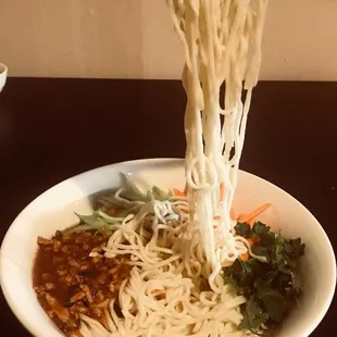 a bowl of noodles with chopsticks