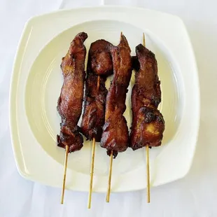 a plate of chicken skewers