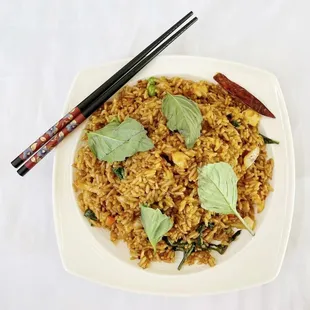 a plate of fried rice with chopsticks
